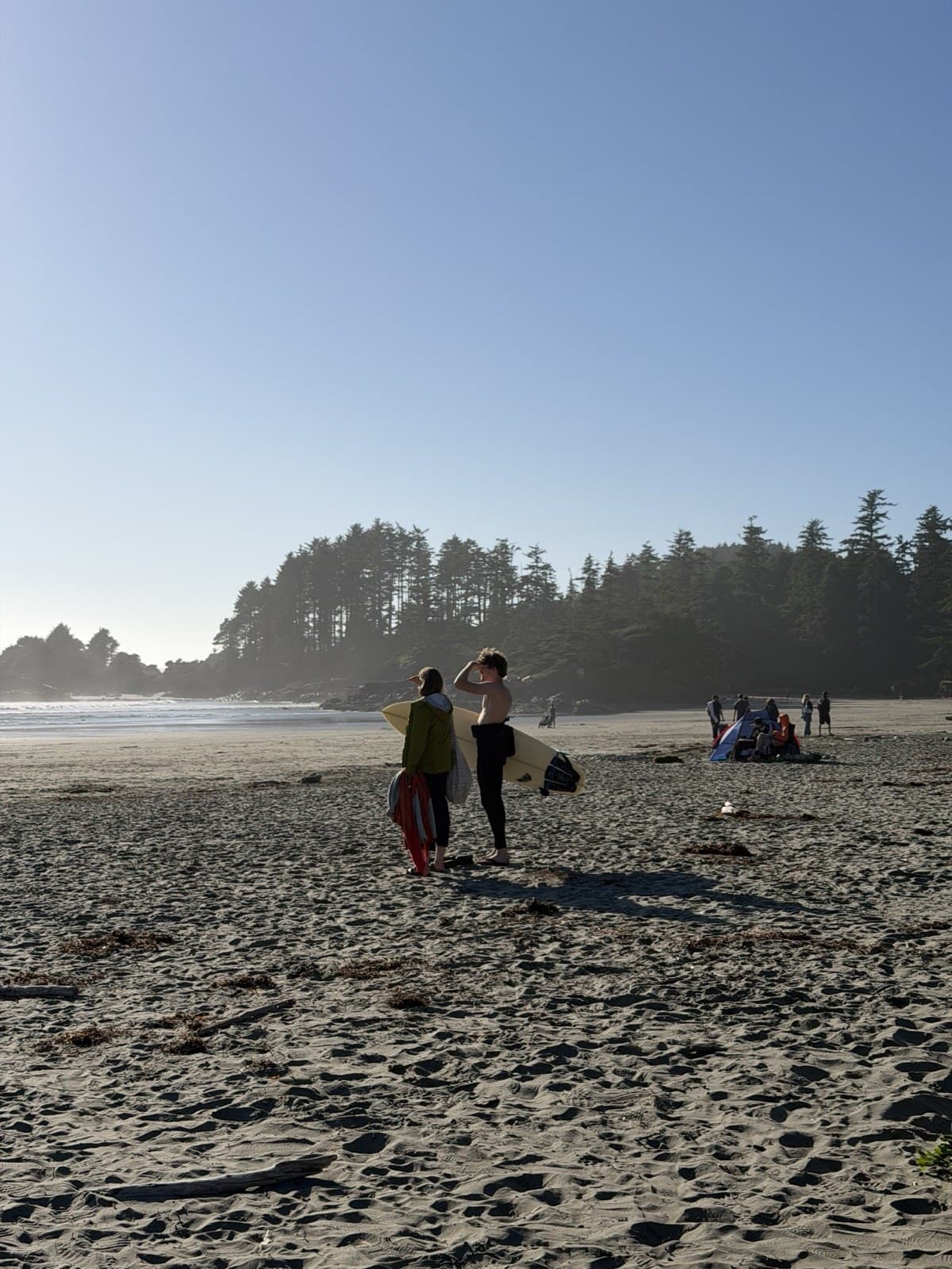 Two travelers with surfboards on a quiet Tofino beach at dawn